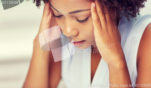 Image of close up of african young woman touching her head