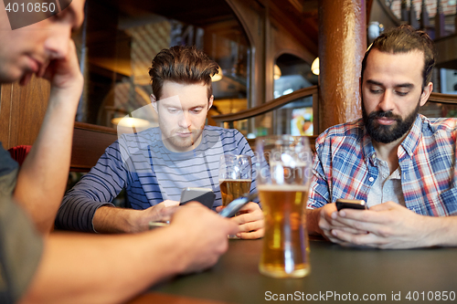 Image of men with smartphones drinking beer at bar or pub
