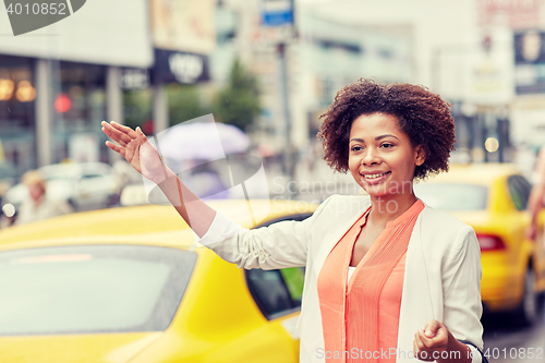 Image of happy african woman catching taxi