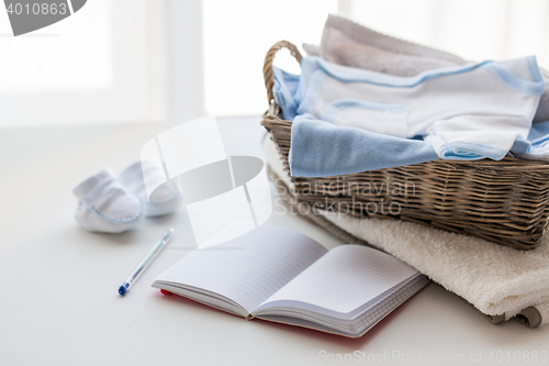 Image of close up of baby clothes for newborn and notebook