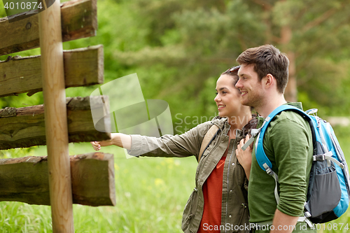 Image of smiling couple at signpost with backpacks hiking