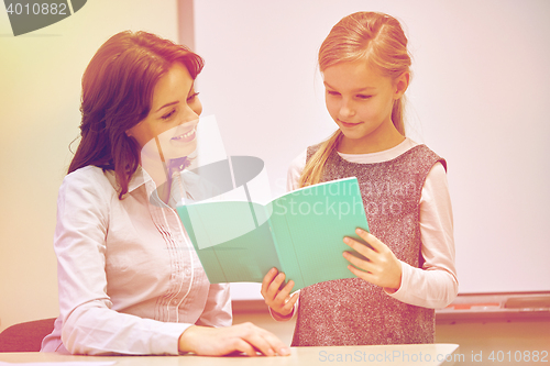 Image of school girl with notebook and teacher in classroom