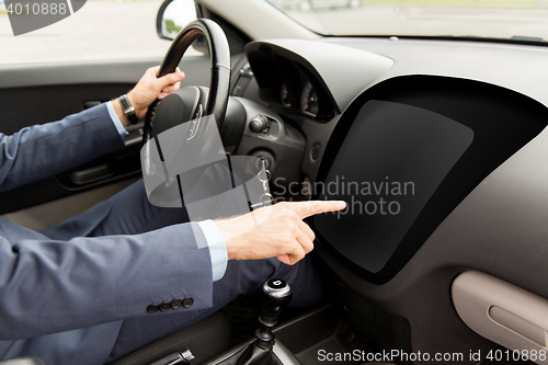 Image of man driving car and pointing to on-board computer