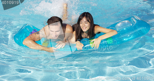 Image of Joyful couple swimming together on floatie in pool