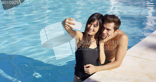 Image of Handsome couple take photo while standing in pool