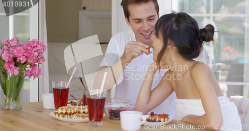 Image of Man feeding his wife fruit at breakfast