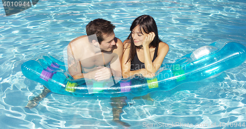 Image of Woman touching face of man floating in pool