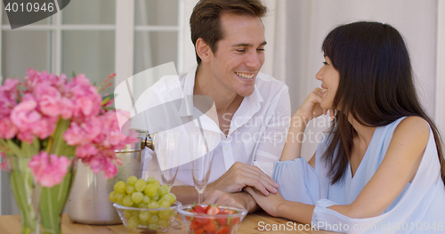 Image of Cute mixed couple enjoying wine and fruit together