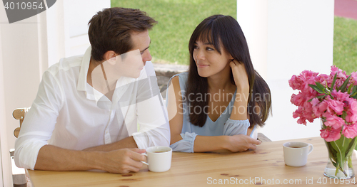 Image of Happy young mixed couple sitting at table