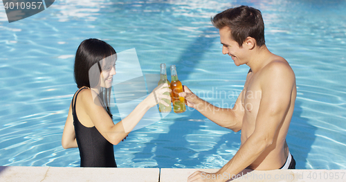 Image of Handsome young couple toasts in swimming pool