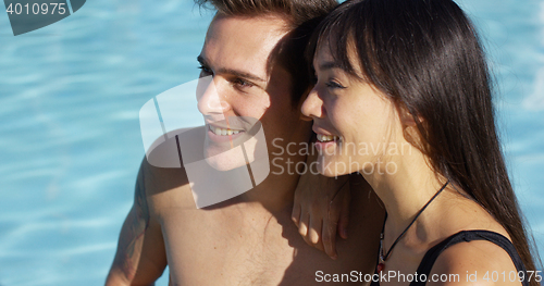 Image of Sunbathing couple sit beside swimming pool