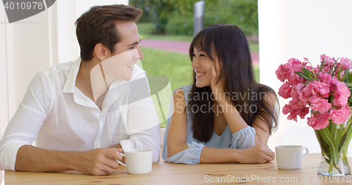 Image of Laughing young adult couple sitting at table