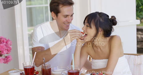 Image of Man feeding his wife fruit at breakfast