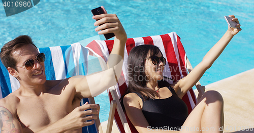 Image of Man and woman taking self portraits at pool