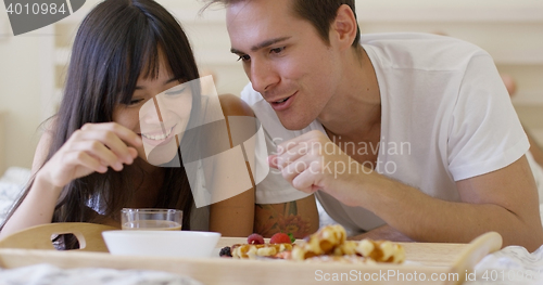 Image of Couple having fruit and waffle breakfast in bed