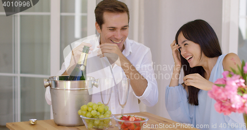 Image of Shocked young couple during champagne opening