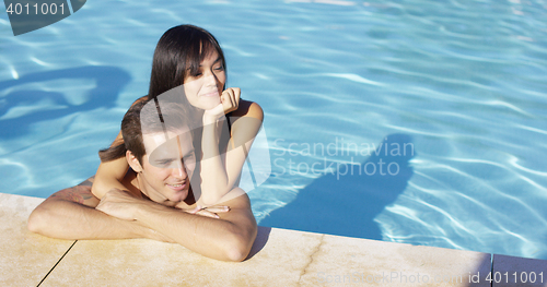 Image of Woman hugs boyfriend and rests elbow on shoulder