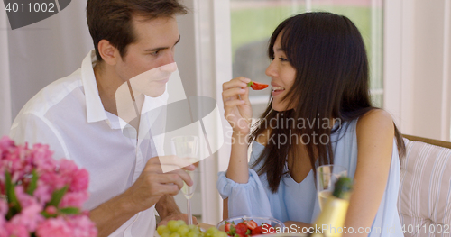 Image of Couple sipping wine and eating fruit