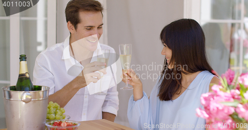 Image of Young happy adult couple toasting champagne