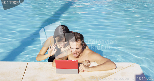 Image of Smiling couple in swimming pool use digital device