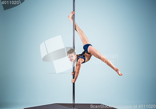 Image of The strong and graceful young girl performing acrobatic exercises on pylon