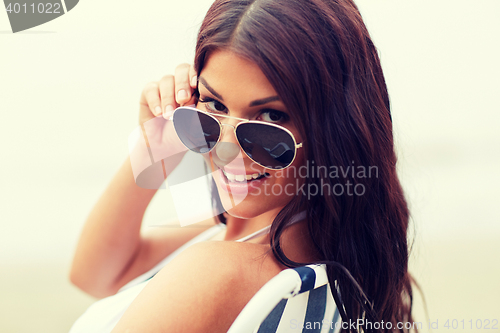 Image of smiling young woman sunbathing in lounge on beach