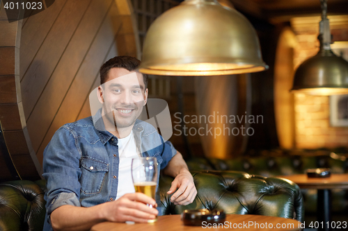 Image of happy man drinking draft beer at bar or pub