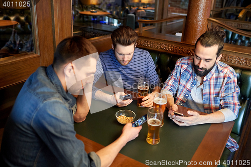 Image of men with smartphones drinking beer at bar or pub