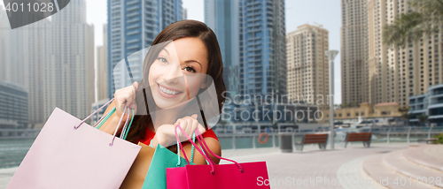 Image of happy woman with shopping bags over dubai city