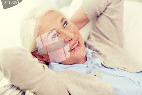 Image of happy senior woman resting on sofa at home