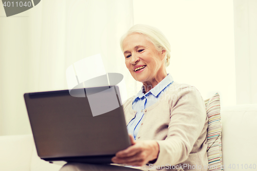 Image of happy senior woman with laptop at home