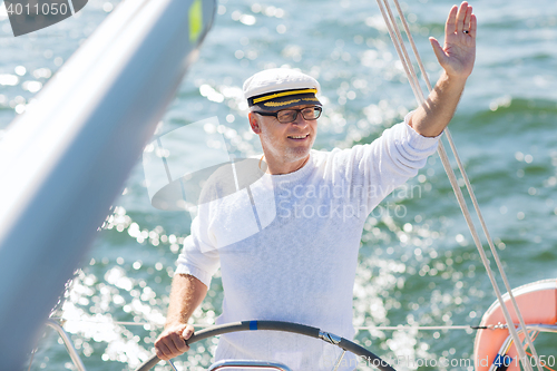 Image of senior man at helm on boat or yacht sailing in sea