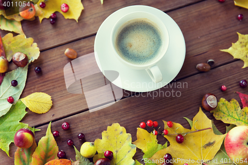 Image of close up of coffee cup on table with autumn leaves