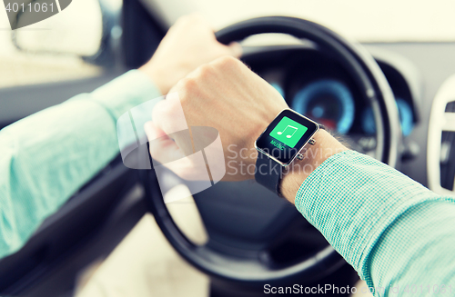 Image of hands with music icon on smartwatch driving car