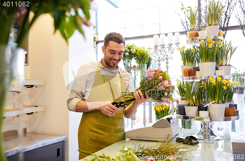 Image of smiling florist man making bunch at flower shop