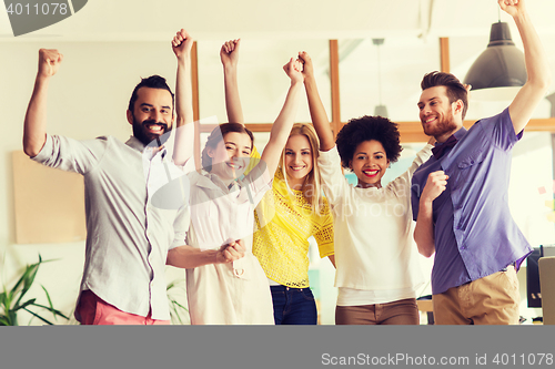 Image of happy creative team celebrating victory in office