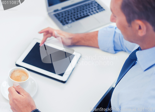 Image of businessman with tablet pc and coffee in office