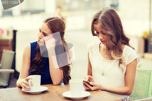 Image of women with smartphones and coffee at outdoor cafe