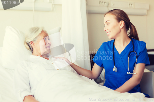 Image of doctor or nurse visiting senior woman at hospital