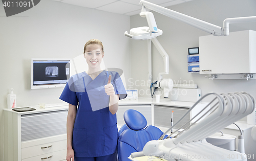 Image of happy female dentist showing thumbs up at clinic