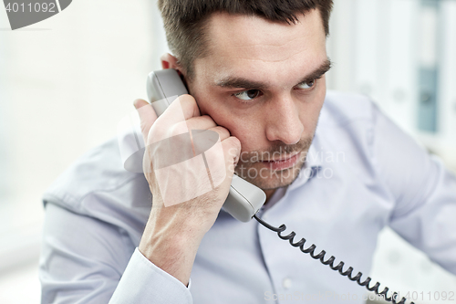 Image of face of businessman calling on phone in office