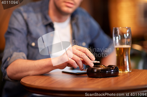 Image of man drinking beer and smoking cigarette at bar