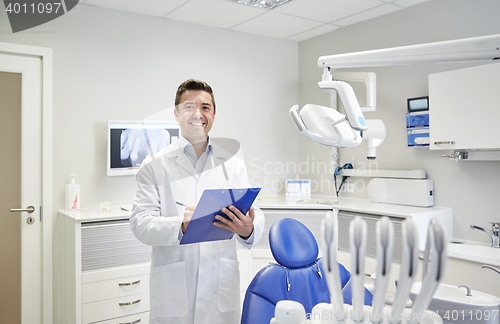 Image of happy male dentist with clipboard at dental clinic