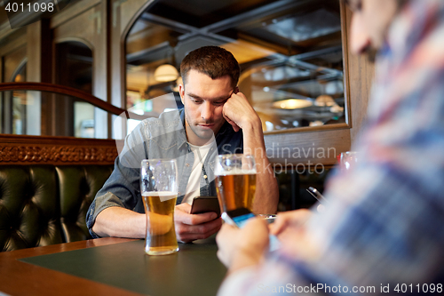 Image of men with smartphones drinking beer at bar or pub