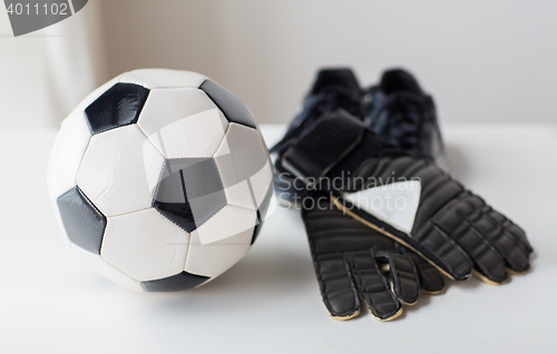 Image of close up of soccer ball, boots and gloves on table