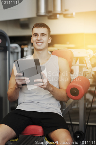 Image of smiling young man with tablet pc computer in gym