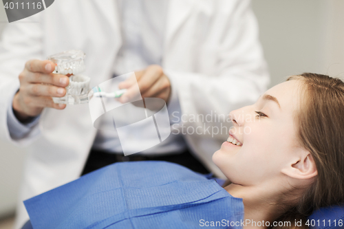 Image of happy dentist showing jaw layout to patient girl