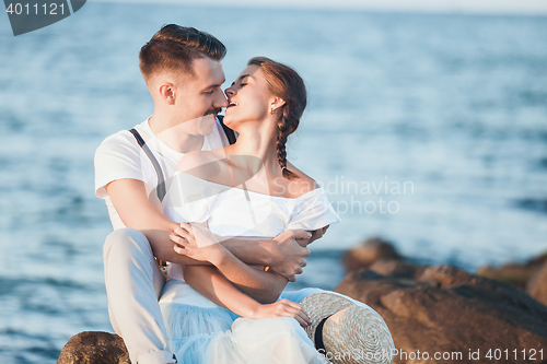 Image of Happy young romantic couple relaxing on the beach and watching the sunset