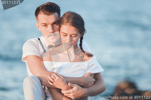 Image of Happy young romantic couple relaxing on the beach and watching the sunset
