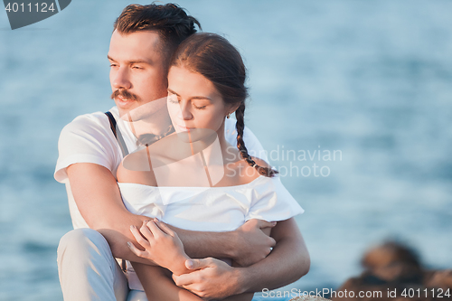 Image of Happy young romantic couple relaxing on the beach and watching the sunset